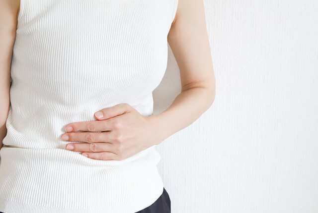 下腹部を手で抑える女性
