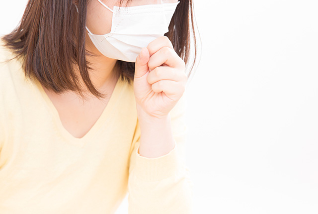 マスクをした女性が口に手を当て咳き込む様子