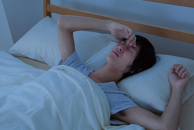 暗い部屋で寝苦しそうにしてる男性